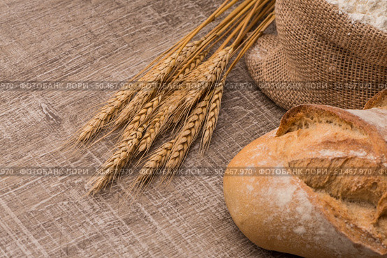 Rustic bread and wheat on an old vintage planked wood table. Стоковое фото, агентство Ingram Publishing / Фотобанк Лори