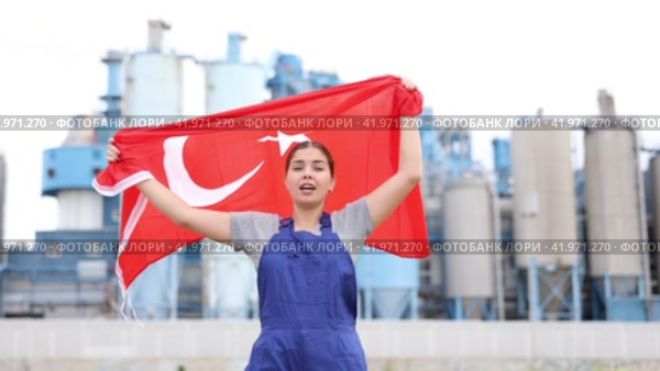 Sad young woman worker standing with big flag of Turkey against background of factory. Стоковое видео, видеограф Яков Филимонов / Фотобанк Лори