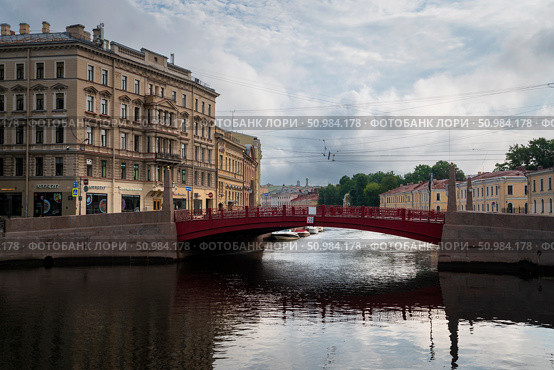 Saint Petersburg, Russia, July 21, 2024: View of the historical residential building of the K.B. Korpus Apartment Building on the Moika River embankment and the Red Bridge. Редакционное фото, фотограф Ula Ulachka / Фотобанк Лори