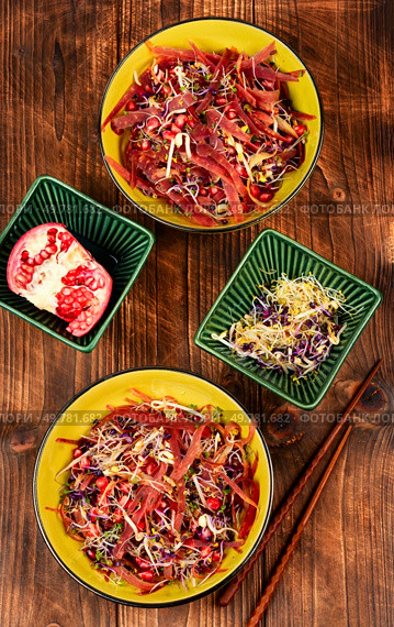 Salad of sprouted alfalfa, beans, red radish with pomegranate seeds and black carrots on wooden rustic background.. Sprouts and pomegranate salad. Стоковое фото, агентство Ingram Publishing / Фотобанк Лори