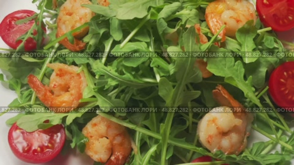 Салат из руккола с тигровыми креветками и помидорами черри на белой тарелке. Вид сверху, крупным планом. Стоковое видео, видеограф Максим Коломыченко / Фотобанк Лори