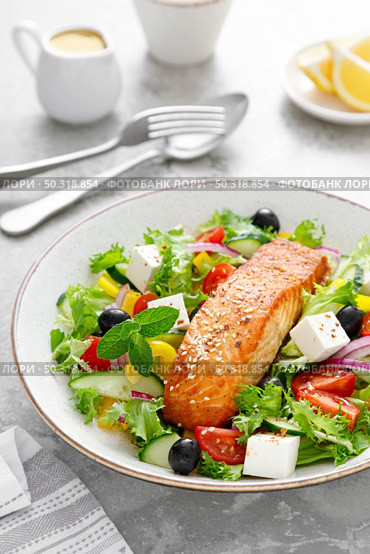Salmon fish salad. Fresh vegetable greek salad with tomato, pepper, lettuce, olives, cucumbers, feta cheese and grilled salmon fish fillet in bowl, healthy food, omega 3, keto diet, mediterranean cusine. Стоковое фото, агентство Ingram Publishing / Фотобанк Лори