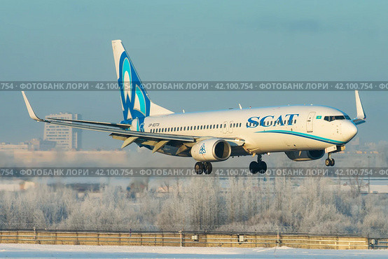 Самолет Boeing 737-800 авиакомпании SCAT Airlines заходит на посадку в аэропорту Пулково зимой, на фоне покрытого белым инеем леса (2019 год). Редакционное фото, фотограф Сергей Крамарев / Фотобанк Лори