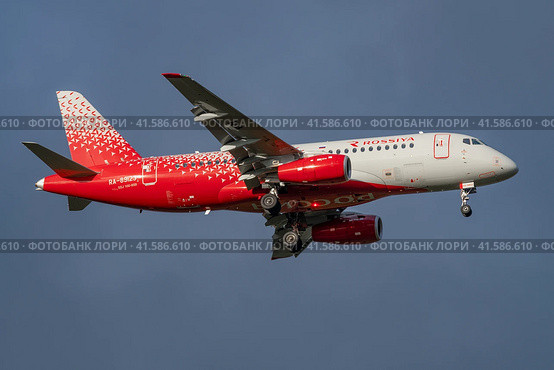 Самолет Сухой SuperJet 100-95B "Клин" (RA-89123) авиакомпании "Россия" крупным планом в облачном сумрачном небе (2023 год). Редакционное фото, фотограф Виктор Карасев / Фотобанк Лори