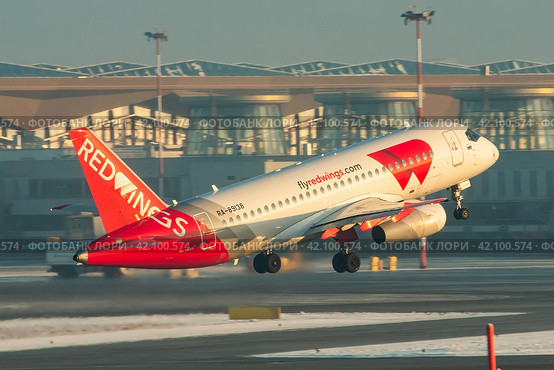 Самолет Сухой SuperJet 100-95LR авиакомпании Red Wings взлетает на фоне старого терминала Пулково-1 (2021 год). Редакционное фото, фотограф Сергей Крамарев / Фотобанк Лори