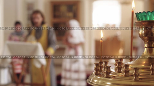 Sanctuary lamp with lit candles in the Orthodox Church - the priest reads a sermon on the background. Стоковое видео, видеограф Константин Шишкин / Фотобанк Лори