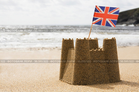 Sandcastle On Empty British Beach With UK Union Jack Flag Flying. Стоковое фото, агентство Ingram Publishing / Фотобанк Лори
