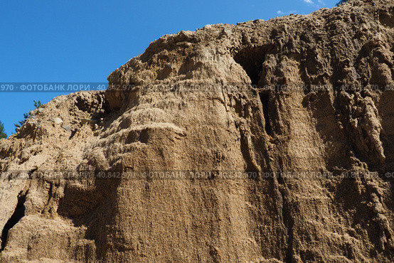 Sandstone is a fragmentary sedimentary rock, a homogeneous or layered aggregate of fragmentary grains and grains of sand bound by any mineral substance, cement. Quarry natural yellow sand wall. Стоковое фото, фотограф Юлия Петровская / Фотобанк Лори