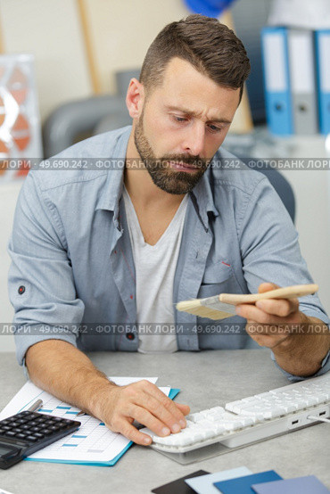 satisfied man standing checking a brush in computer. Стоковое фото, агентство Ingram Publishing / Фотобанк Лори