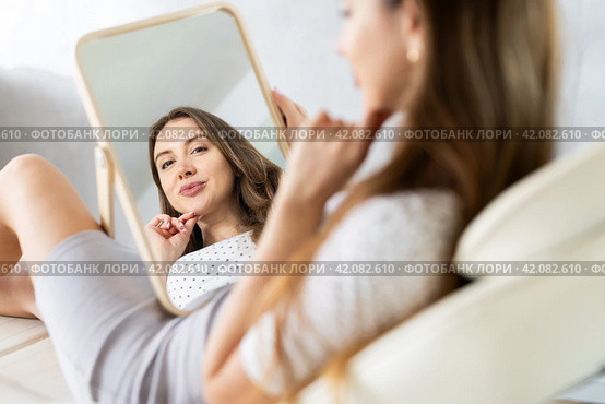 Satisfied young woman patient holding mirror lying on clinical chair. Стоковое фото, фотограф Яков Филимонов / Фотобанк Лори