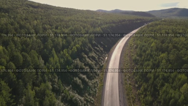 Scenic winding road through lush forest landscape at sunset. Стоковое видео, видеограф Гурьянов Андрей / Фотобанк Лори