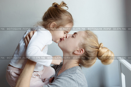 Счастливая мама держит на руках и целуе свою дочь / Happy mom hugs and kisses laughing daughter, holding her in her arms. family, motherhood concept. Стоковое фото, фотограф Сергей Тиняков / Фотобанк Лори
