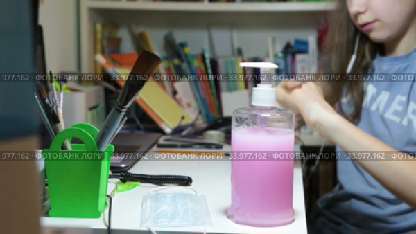 School age girl disinfecting her hands with liquid antiseptic while doing home exercises at the desk. Стоковое видео, видеограф Кекяляйнен Андрей / Фотобанк Лори