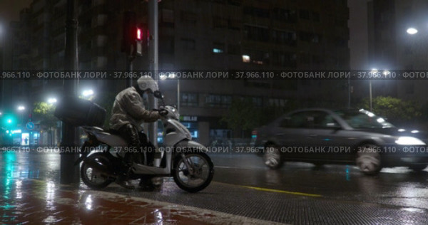 Scooter driver setting off under the rain in night city (2022 год). Редакционное видео, видеограф Данил Руденко / Фотобанк Лори