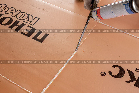 Sealing of seams of polyurethane boards Penoplex with mounting foam from a cylinder during installation of underfloor heating (2024 год). Редакционное фото, фотограф Коханова Наталья / Фотобанк Лори