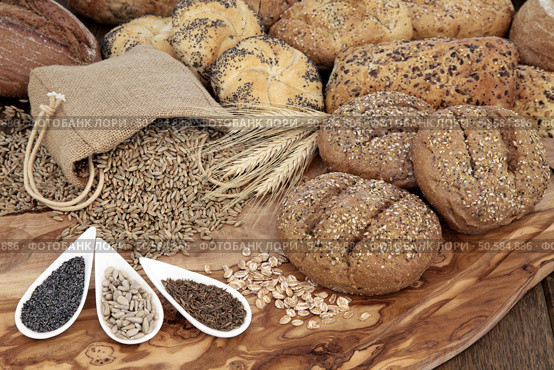 Seeded bread roll selection with wheat sheaths, rye grain in a hessian sack wiith chia, sunflower and caraway seed on an olive wood board. Стоковое фото, агентство Ingram Publishing / Фотобанк Лори