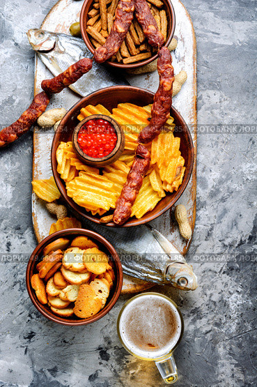 Selection of beer and snacks.Chips, fish, beer sausages on the table. Snacks for beer. Стоковое фото, агентство Ingram Publishing / Фотобанк Лори