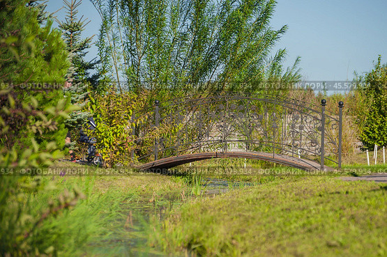 Semicircular metal bridge over a stream (2024 год). Стоковое фото, фотограф Evgenii Predibailo / Фотобанк Лори