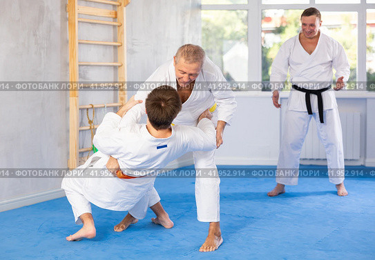 Senior man, karate sensei, engaging kumite with young guy in training room. Стоковое фото, фотограф Яков Филимонов / Фотобанк Лори