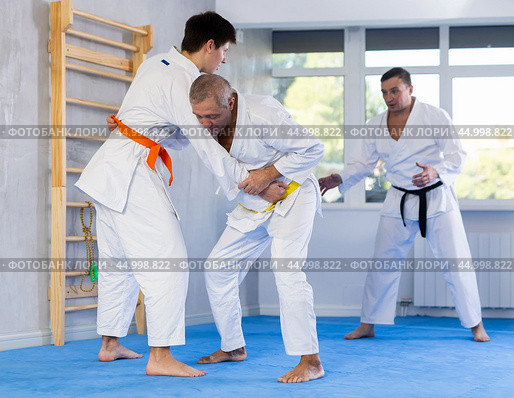 Senior man, karate sensei, engaging kumite with young guy in training room. Стоковое фото, фотограф Яков Филимонов / Фотобанк Лори
