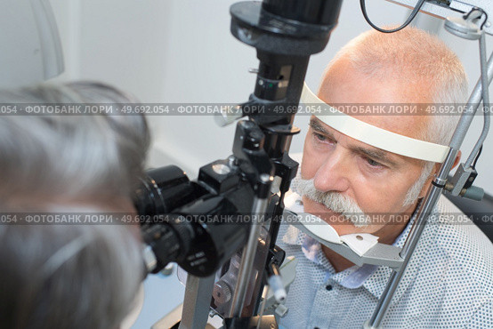 senior man looking into slit lamp at clinic. Стоковое фото, агентство Ingram Publishing / Фотобанк Лори