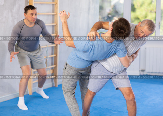 Senior man practicing basic protection skills in training bout during self-defense course. Стоковое фото, фотограф Яков Филимонов / Фотобанк Лори
