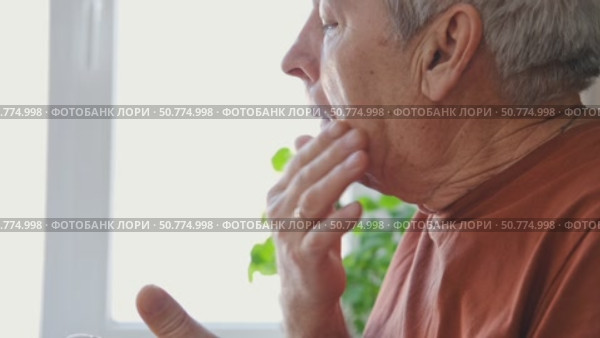 Senior Man shaving his face. Old male shaves beard and mustache with shaver. Elderly gray haired man looking at the mirror, applies shaving cream foam and using razor. Skin hygiene. Daily body care. Стоковое видео, видеограф Марина Демидюк / Фотобанк Лори