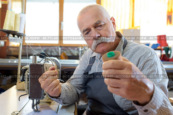 senior man threading old fashioned manual sewing machine. Стоковое фото, агентство Ingram Publishing / Фотобанк Лори
