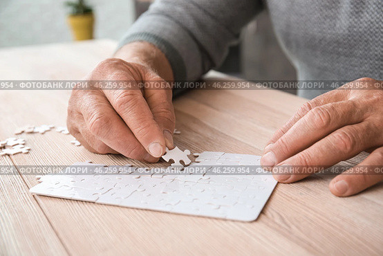 Senior man with Parkinson syndrome doing puzzle at home, closeup. Стоковое фото, фотограф Pixel_shot / Фотобанк Лори