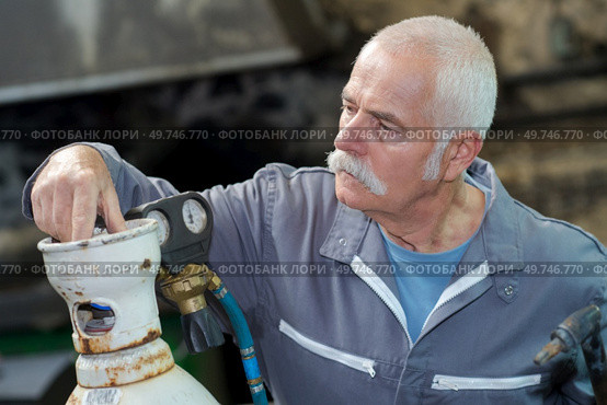 senior welder setting gas bottle before welding. Стоковое фото, агентство Ingram Publishing / Фотобанк Лори