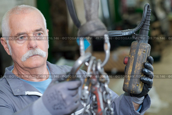 senior worker holding a hook in a factory. Стоковое фото, агентство Ingram Publishing / Фотобанк Лори