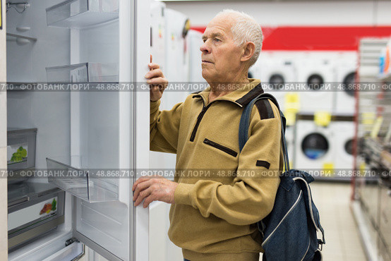 Senor man pensioner buying fridge in showroom of electrical appliance store. Стоковое фото, фотограф Татьяна Яцевич / Фотобанк Лори