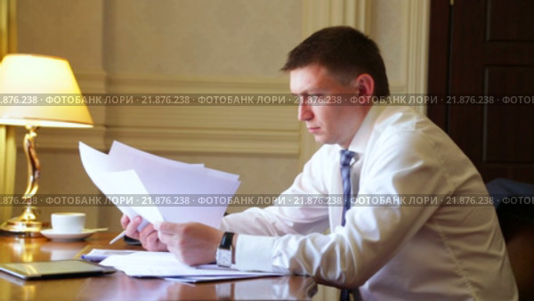 Серьезный бизнесмен работает с документами в номере гостиницы. Стоковое видео, видеограф Виталий Зверев / Фотобанк Лори
