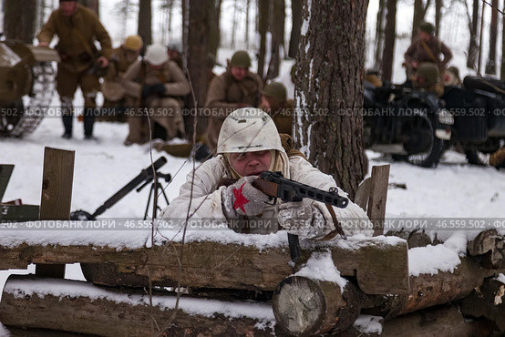 Sestroretsk, Russia - February 19, 2023: In a snowy forest, soldiers in winter gear meticulously recreate WWII battle tactics and equipment. Редакционное фото, фотограф Aleksandr Golubev / Фотобанк Лори