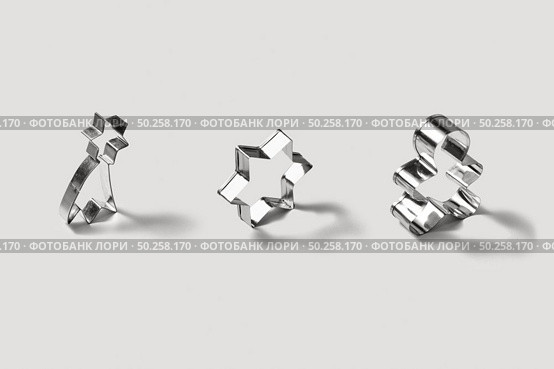 Set of stainless steel cookie-cutters for baking homemade christmas cookies, in the shape of stars and gingerbread on a light grey background with soft shadows.. Vertically standing stainless steel moulds set for cookies. Стоковое фото, агентство Ingram Publishing / Фотобанк Лори