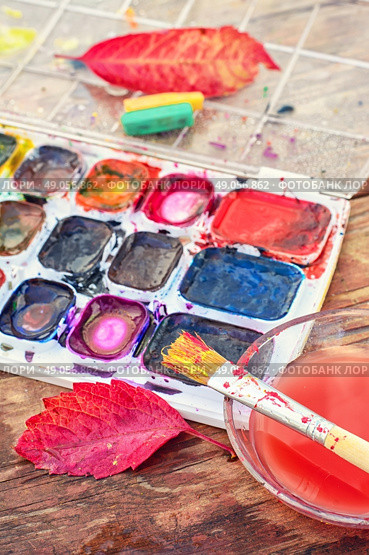 set of watercolors,a little bowl of water to clean the brush and autumn leaves. Стоковое фото, агентство Ingram Publishing / Фотобанк Лори