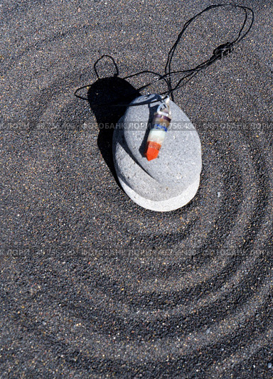 Seven chakras healing crystals pendulum. Meditation and relaxation spiritual esoteric practice. Healing crystals pendulum on black sand background. Стоковое фото, агентство Ingram Publishing / Фотобанк Лори
