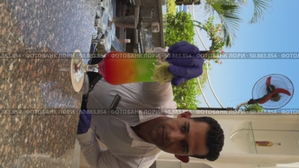 Sh arm eli Sheikh Egypt June 12 2025.A male bartender carefully prepares a vibrant layered cocktail, garnished with colorful fruits. The drink shimmers with a spectrum of colors, creating a visually. Редакционное видео, видеограф Zita Khasanova / Фотобанк Лори