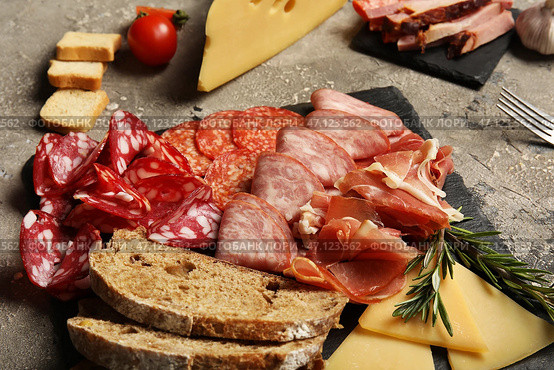 Шиферная тарелка с ассортиментом вкусных мясных деликатесов, хлеба и сыра на сером фоне. Стоковое фото, фотограф Pixel_shot / Фотобанк Лори