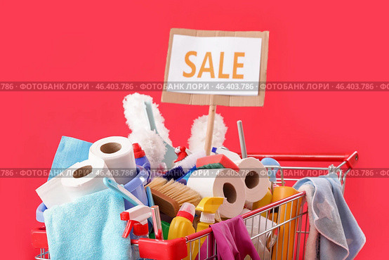 Shopping cart full of cleaning supplies and word SALE on red background. Стоковое фото, фотограф Pixel_shot / Фотобанк Лори