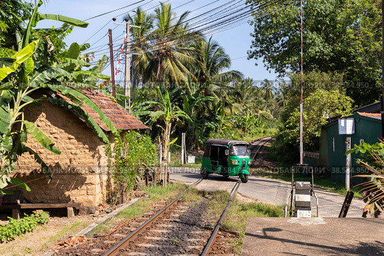 Шри-Ланка. Унаватуна. Транспорт тук-тук на железнодорожном переезде. Sri Lanka. Unawatuna. Transport tuk-tuk at a railway crossing. (2022 год). Редакционное фото, фотограф Алексей Смышляев / Фотобанк Лори