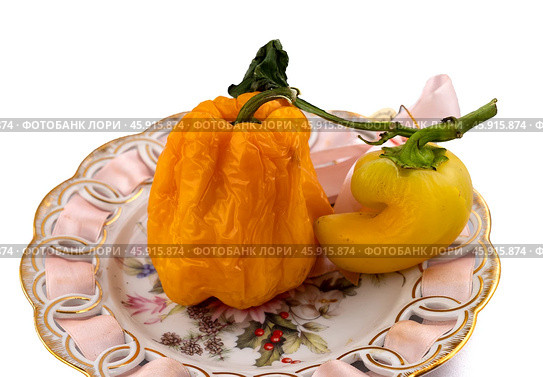 Shriveled fruits of yellow sweet pepper lie on a plate White background. There is a place for inserts. Стоковое фото, фотограф Андреева Тамара Викторовна / Фотобанк Лори