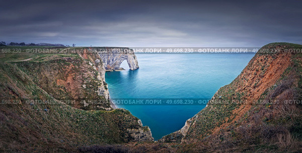 Sightseeing panoramic view to the Porte d’Aval natural arch cliff washed by Atlantic ocean waters at Etretat, Normandy, France. Beautiful coastline scenery with famous Falaise d’Aval. Стоковое фото, агентство Ingram Publishing / Фотобанк Лори
