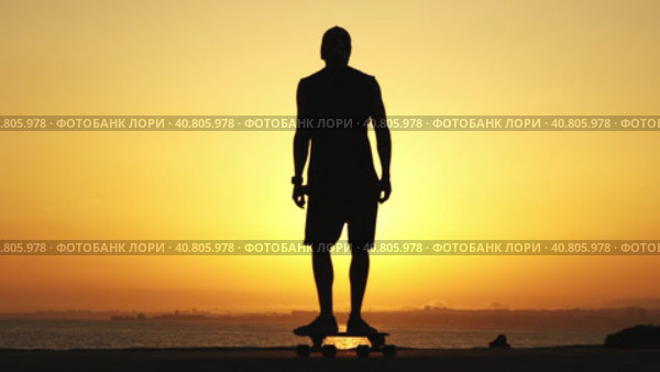 Silhouette of a man skating on a longboard at sunset. Стоковое видео, видеограф Константин Шишкин / Фотобанк Лори