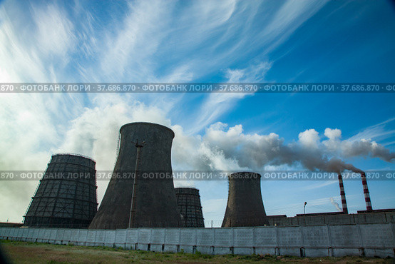 Silhouette view on Pavlodar thermal power plant. Cooling towers left. Smoke stacks with white smoke right. Blue sky with clouds. Стоковое фото, фотограф Alexey Rezvykh / Фотобанк Лори
