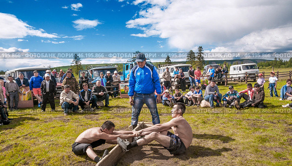 Силовые состязания среди молодых людей, местные жители - зрители, на народном празднике Ысыах в селе Томтор ( Республика САХА, Якутия, Оймяконский район ) (2010 год). Редакционное фото, фотограф Павел Просянов / Фотобанк Лори