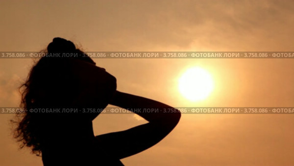 Силуэт женщины на фоне вечернего неба. Поправляет волосы. Стоковое видео, видеограф Losevsky Pavel / Фотобанк Лори