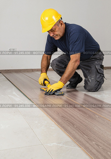 Skilled worker measuring wooden flooring in home renovation, craftsmanship. Стоковое AI-изображение, AI-художник Ольга Невская / Фотобанк Лори