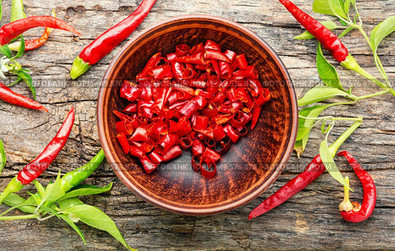 Sliced red hot chili peppers on on wooden background. Paprika powder and chili peppe. Стоковое фото, агентство Ingram Publishing / Фотобанк Лори