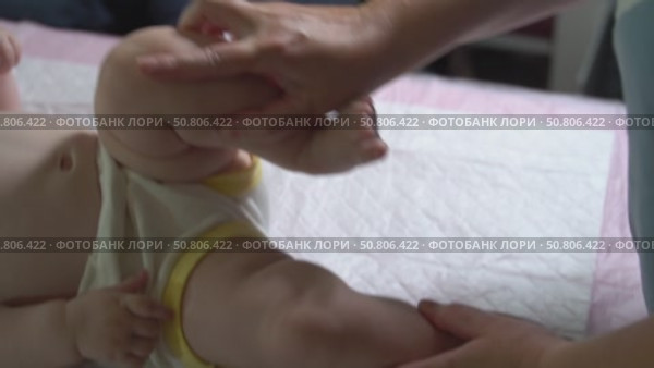 Slow-motion video of an infant under one year receiving a leg massage to enhance left hip joint mobility. Pediatric physiotherapy session. Стоковое видео, видеограф Татьяна Степанищева / Фотобанк Лори